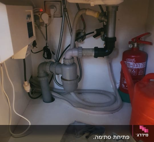 צנרת מתחת לכיור עם ברזים וצינורות